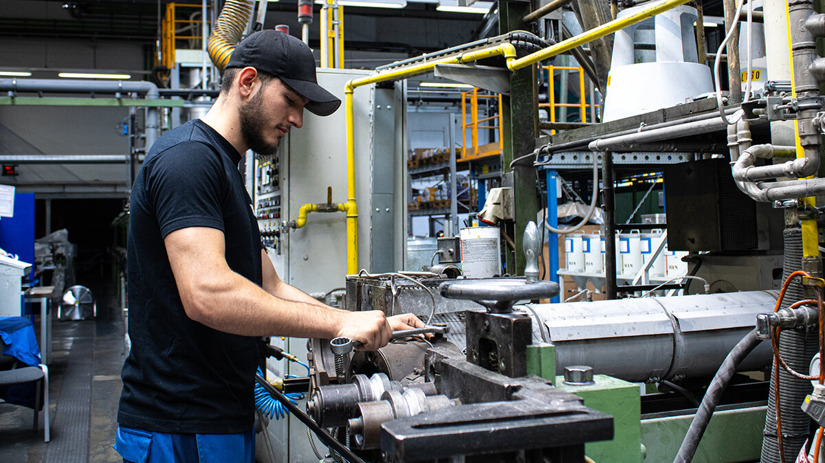 Altin schraubt mit einem Schraubenschlüssel an einem Extruder.