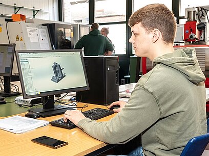 Ein junger Mann erstellt am Computer ein Modell mit einem CAD-System.