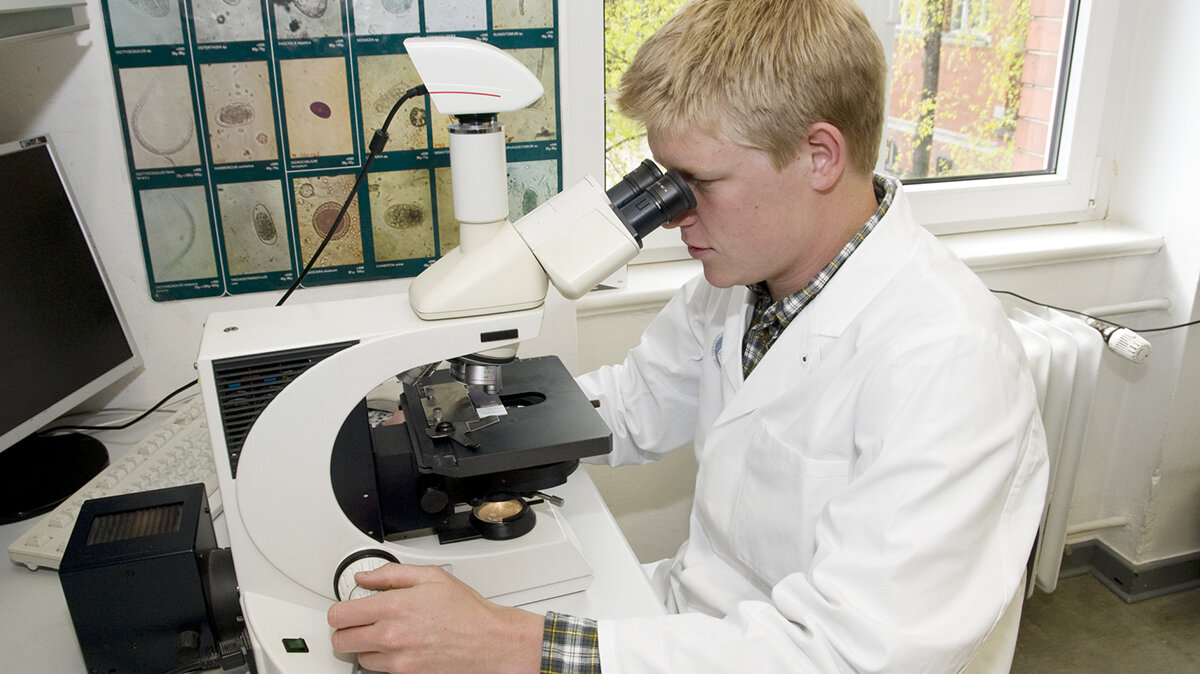 Ein Mann untersucht etwas mit dem Mikroskop.
