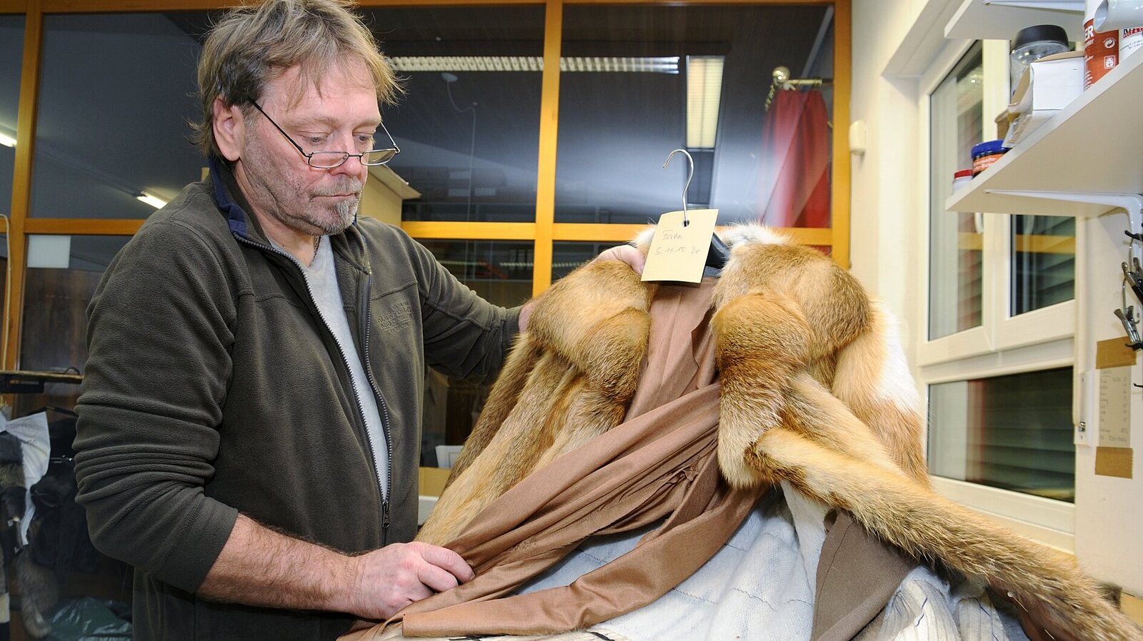 Ein Mann begutachtet einen Pelzmantel für eine Umarbeitung.