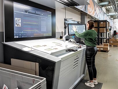 Eine junge Frau arbeitet an einer Offsetdruckmaschine.