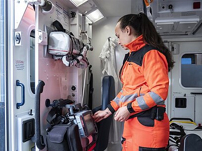 Eine junge Frau in Uniform arbeitet an einem Gerät im Krankenwagen.