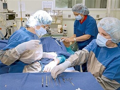 Eine Chirurgin und zwei OP-Assistentinnen führen eine Operation durch.