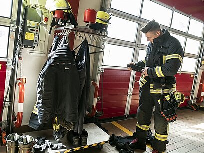 Ein junger Feuerwehrmann legt seine Schutzkleidung an.
