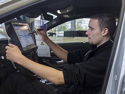 Ein Mann bedient ein Touchpad für eine Messung in einem Auto.