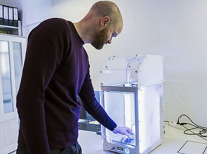 Ein Mann bedient einen 3D-Drucker.