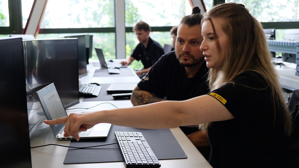 Ayliah zeigt ihrem Ausbilder etwas auf dem Computer.