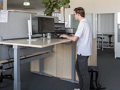 Ein junger Mann arbeitet an einem Comuter mit mehreren Bildschirmen.