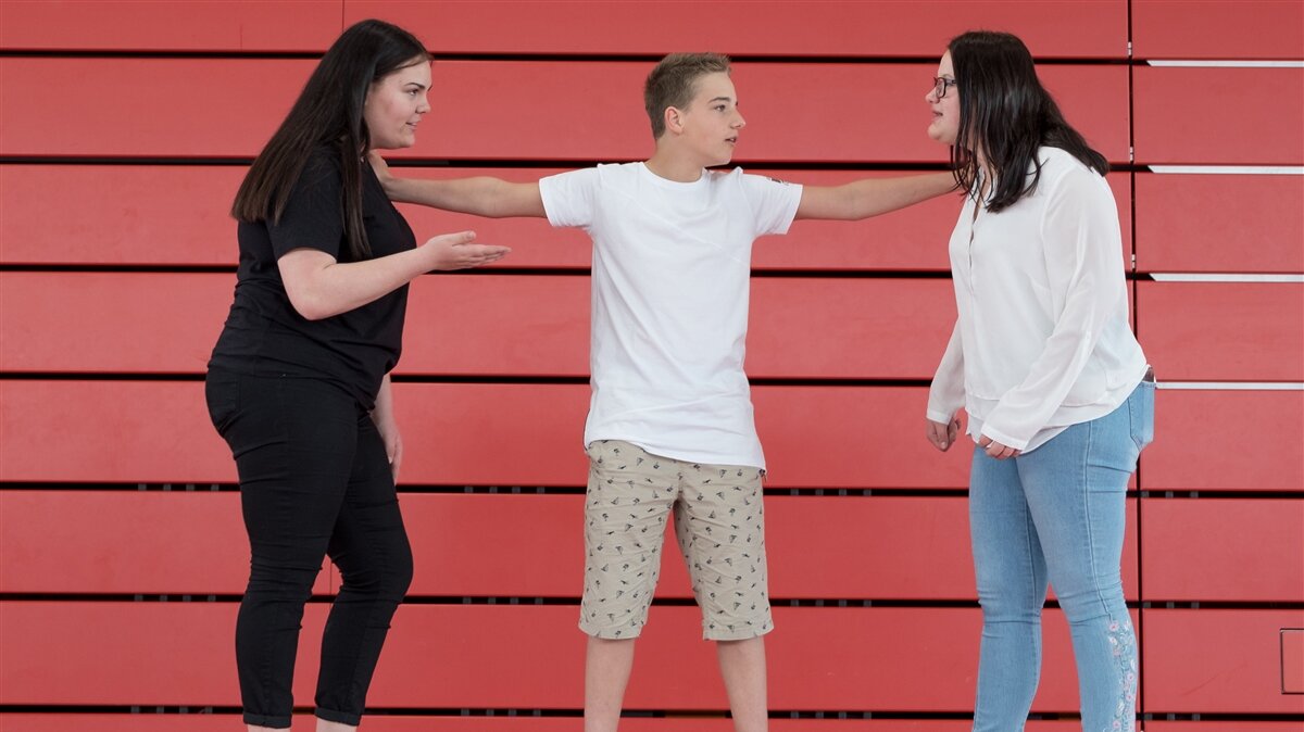 Ein Junge schlichtet den Streit zwischen zwei Mädchen.