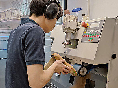 Ein junger Mann arbeitet an einer Schleifmaschine.