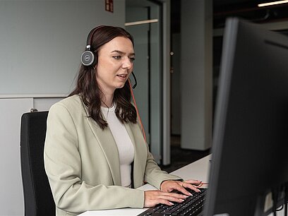 Eine junge Frau sitzt am Computer und hat eine Besprechung.