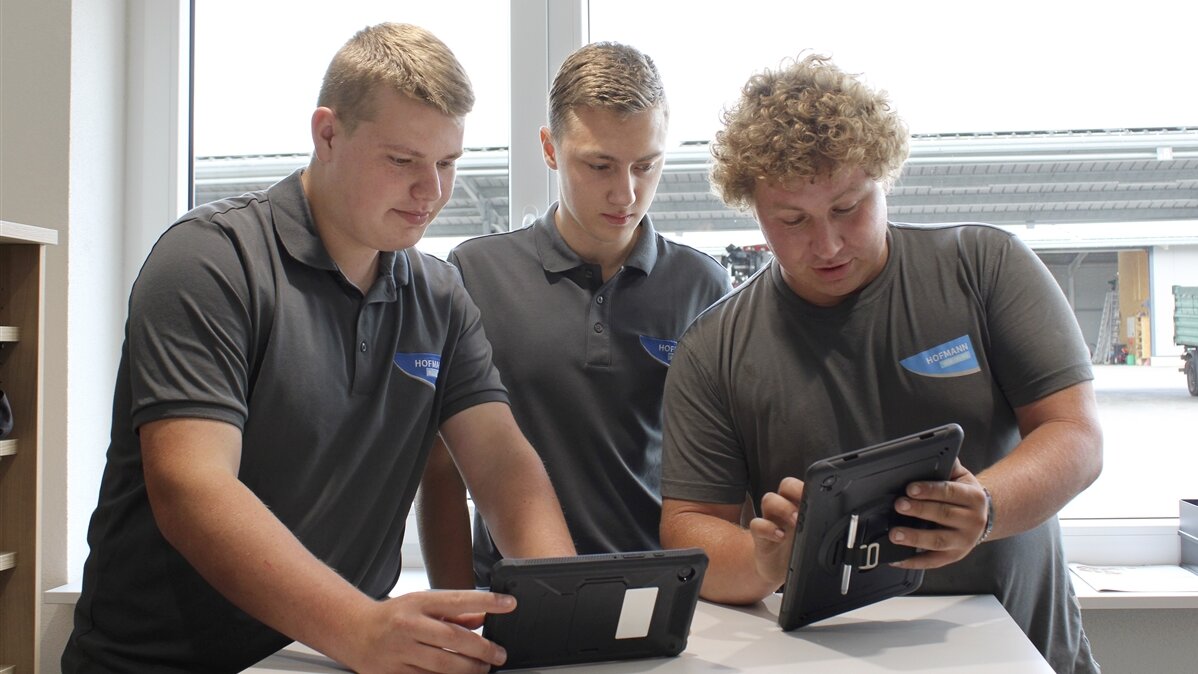 Jan und Lucas Vorgesetzer zeigt ihnen Aufgaben auf einem Tablet.