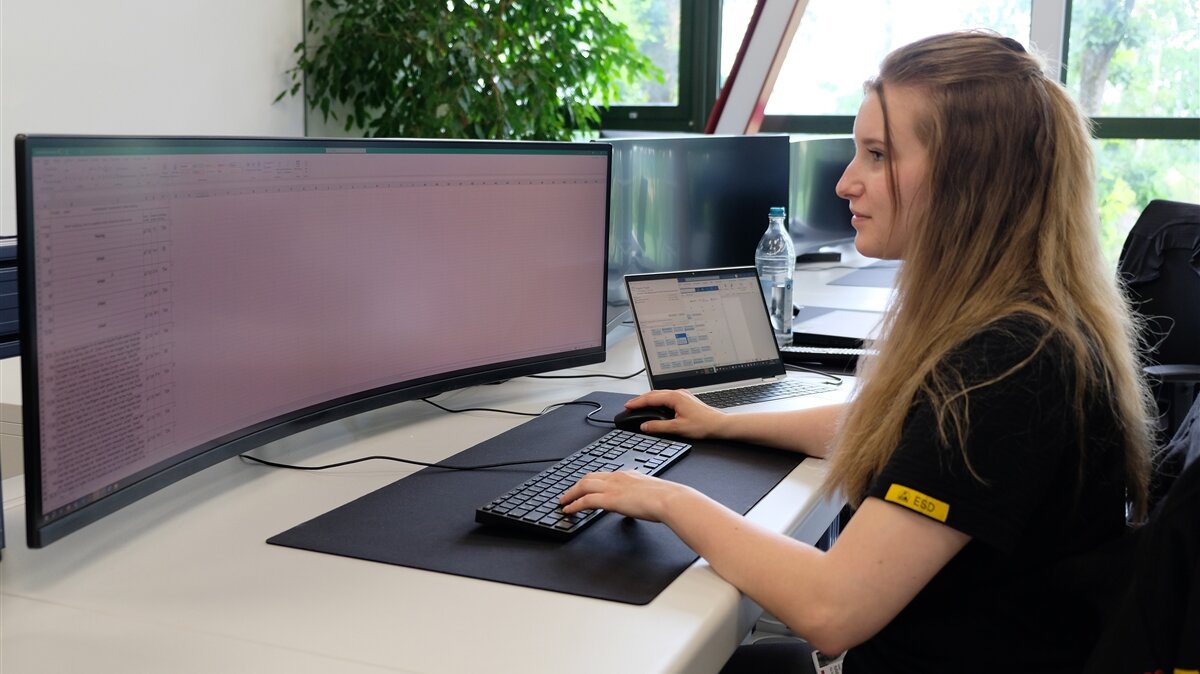 Ayliah sitzt an ihrem Schreibtisch und arbeitet am Computer.