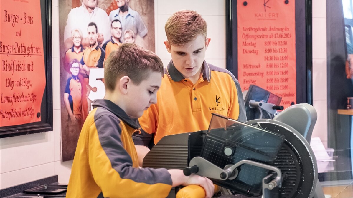 Stefan und sein Bruder schneiden Wurst mit der Schneidemaschine.