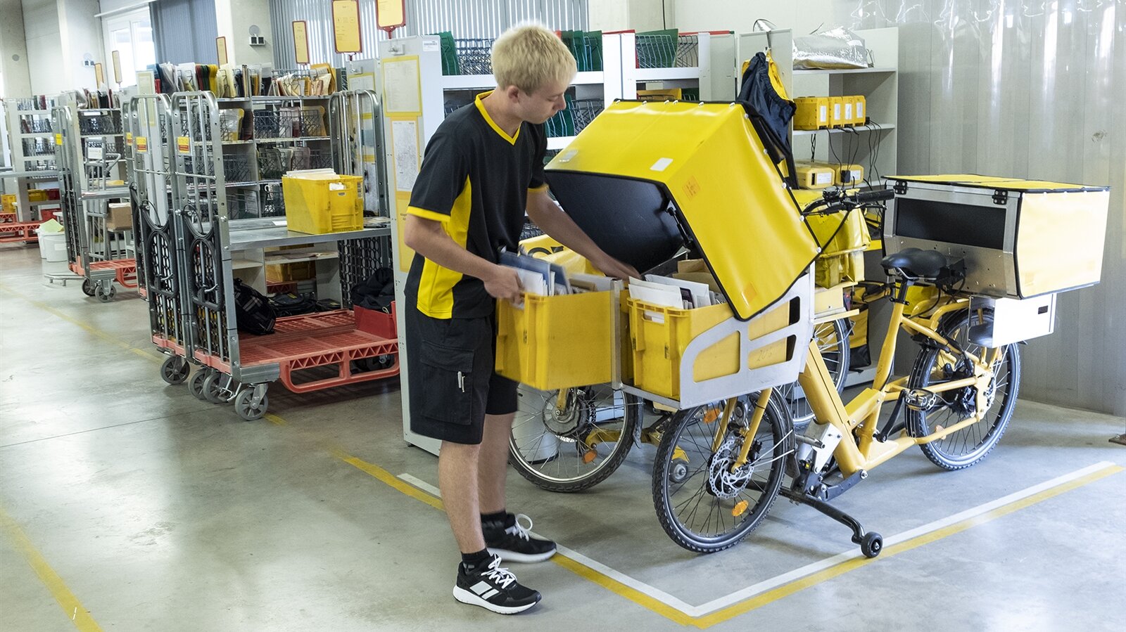 Simon packt die sortierte Post in große Taschen an seinem Fahrrad.