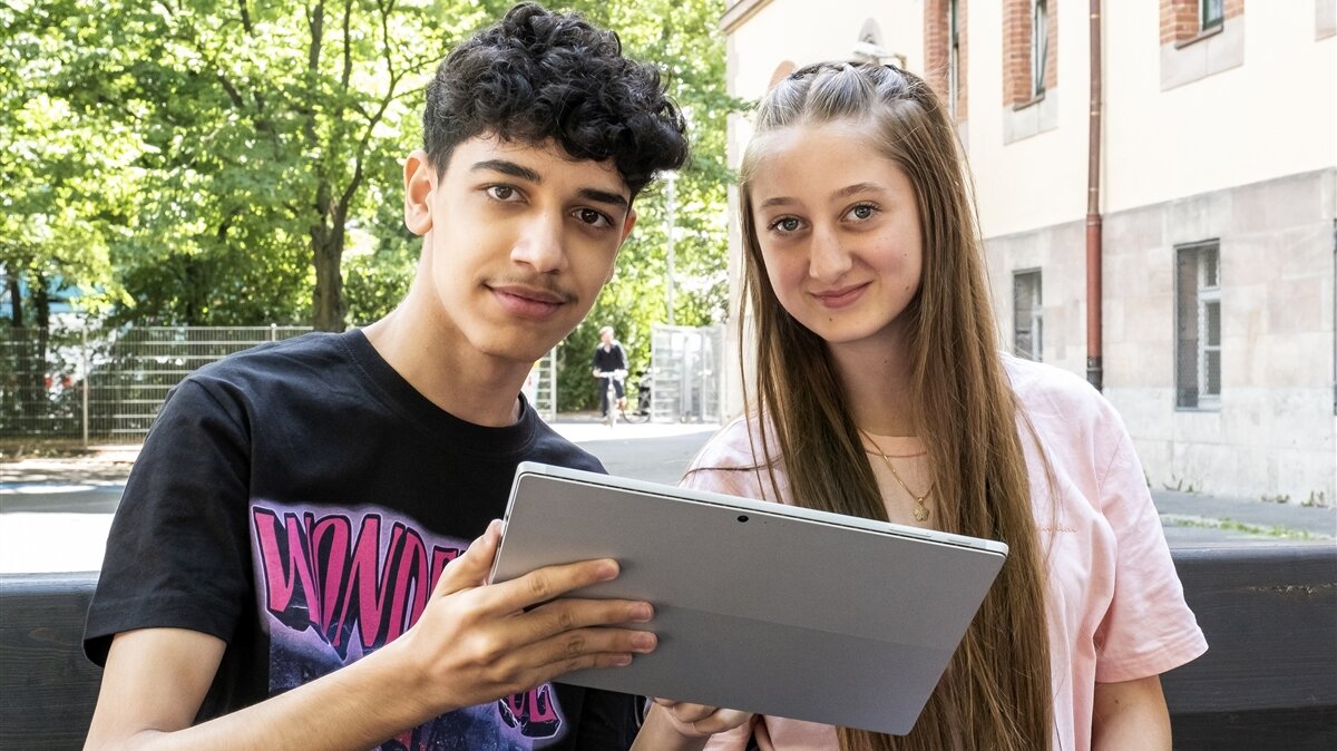 Eine Schülerin und ein Schüler arbeiten gemeinsam an einem Tablet.