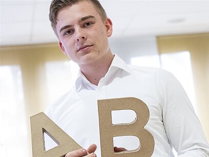 Ein Azubi hält die Buchstaben A und B in der Hand