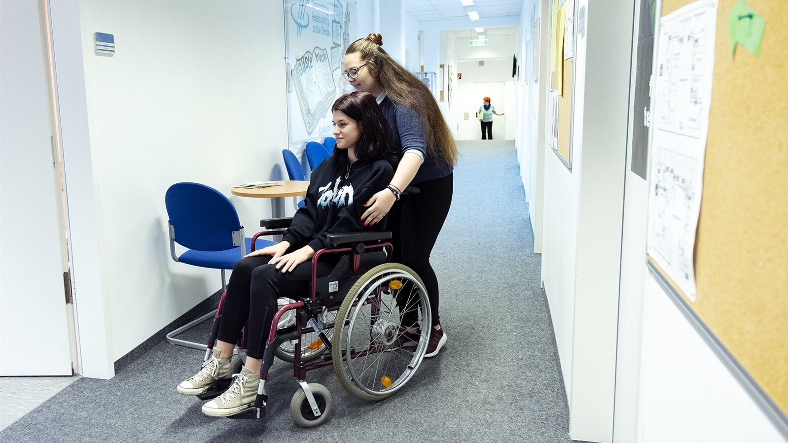 Victoria bewegt eine Patientin im Rollstuhl.