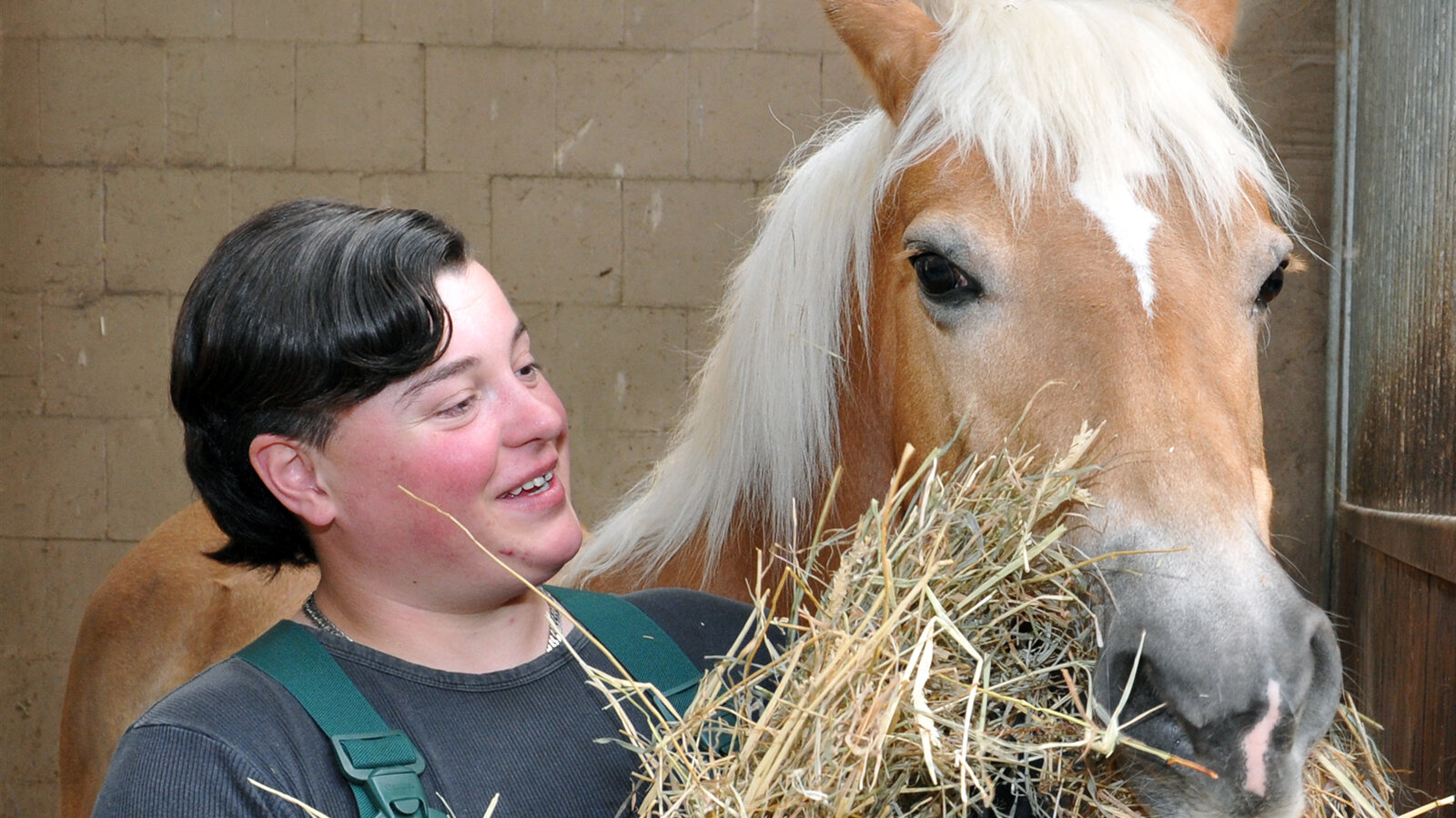 Jennifer füttert ein Pferd mit Heu.