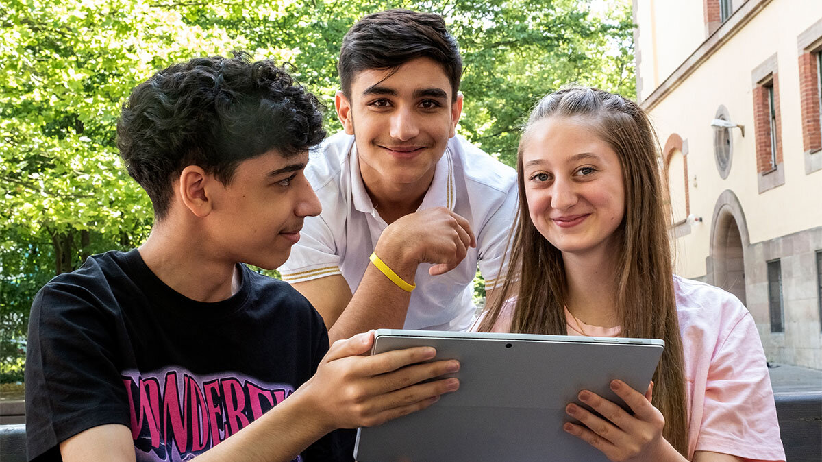 Gruppenbild von 3 Jugendlichen vor einem Tablet