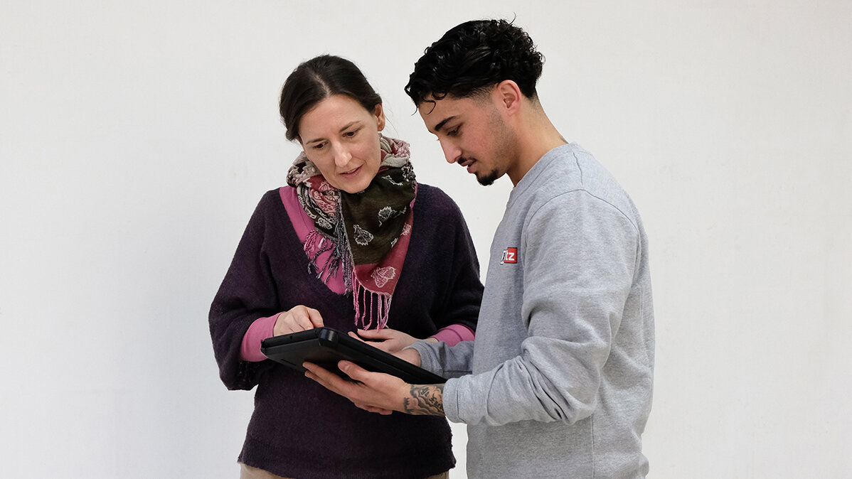 Zainal bespricht sich mit der Kundin anhand einer Skizze auf seinem Tablet.