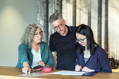 Eine junge Frau mit Bewerbungsunterlagen wird von ihren Eltern beraten.