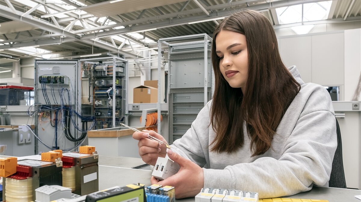 Melissa klebt mit einer Pinzette gelbe Aufkleber auf die Bauteile. 