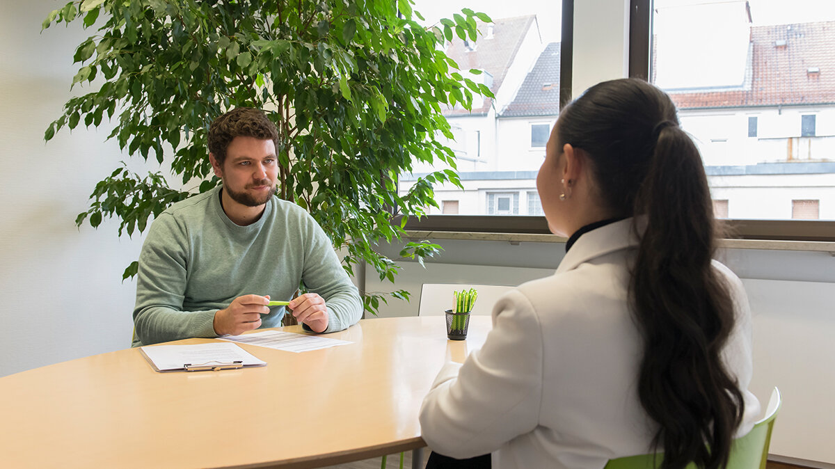 Ein junger Mann sitzt einer Frau am Tisch gegenüber.