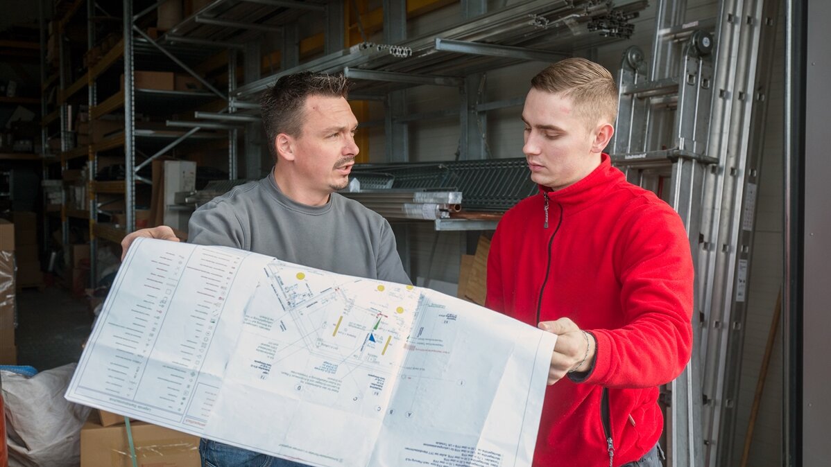 Zwei Elektroniker schauen sich einen Plan an.