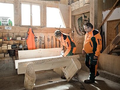 Zwei Fachkräfte prüfen eine aus Holz gefertigte Bank.