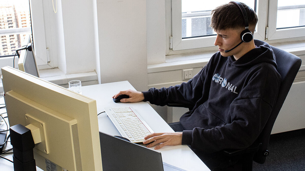 Paul sitzt an seinem Arbeitsplatz und nimmt am digitalen Abschlussmeeting teil.