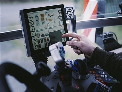 Eine Person steuert eine landwirtschaftliche Maschine über einen Bildschirm. 