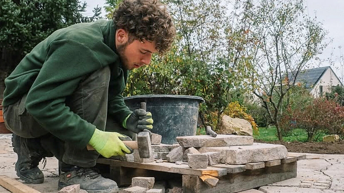 Ein junger Mann bearbeitet Steine mit Hammer und Meißel.