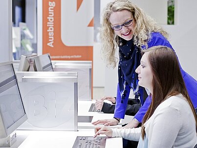 Ein Mitarbeiter eines BiZ unterstützt einen Jugendlichen, der im BiZ am Computer arbeitet.