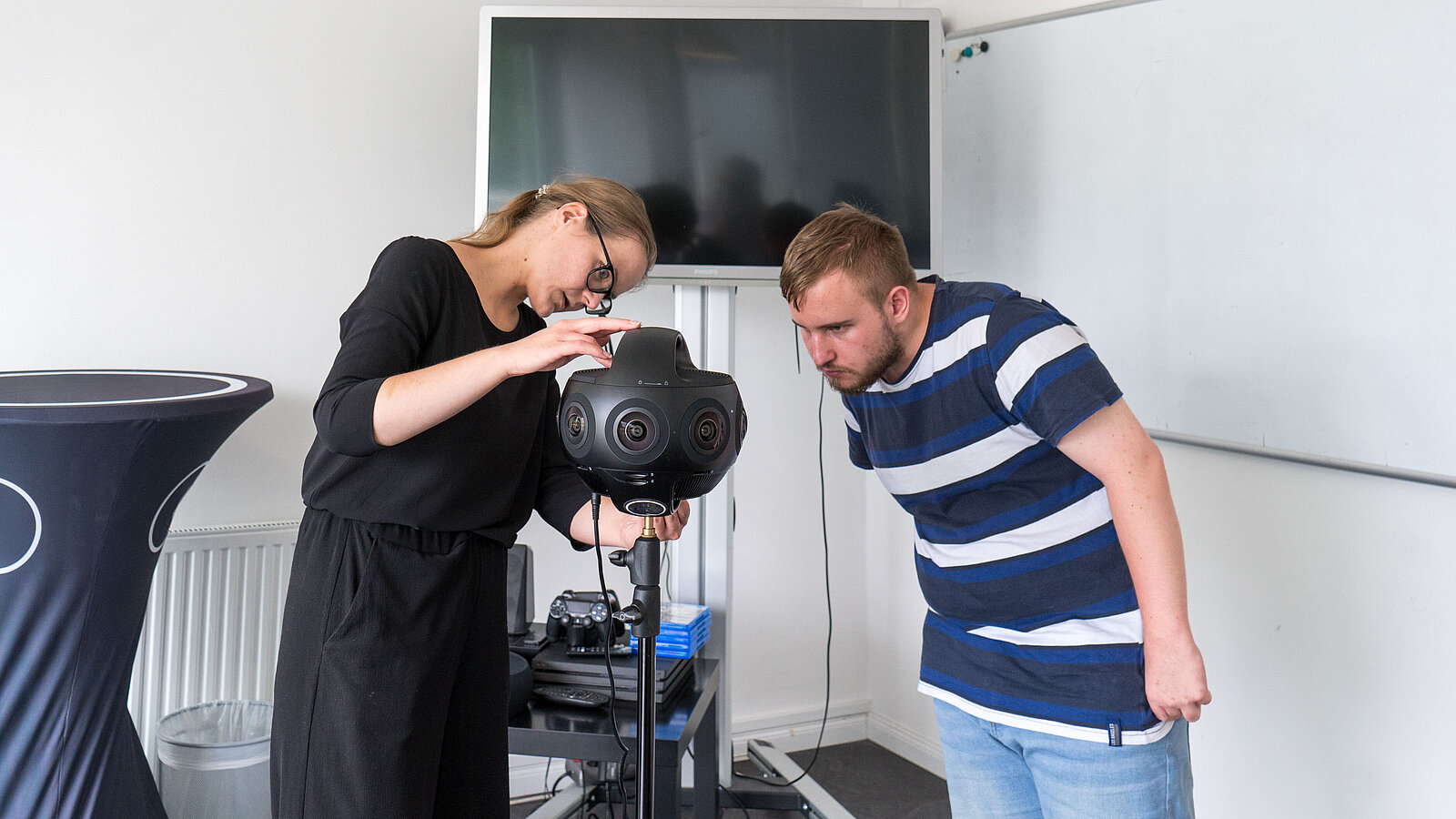 Eine junge Frau und ein junger Mann bauen ein Gerät mit Kameralinsen auf.