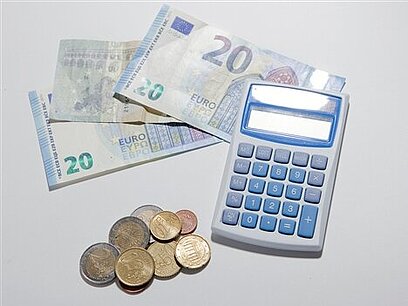 Neben einem Taschenrechner liegen Euro-Geldscheine und -Münzen.