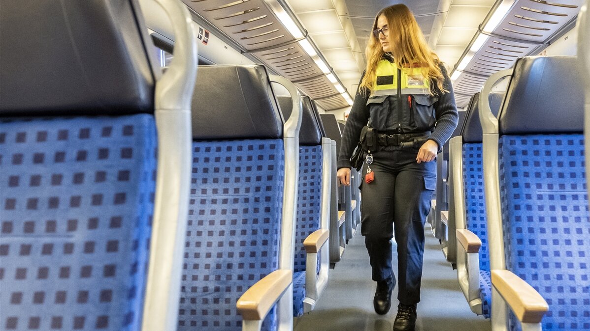 Eine junge Frau in Sicherheitsjacke geht durch einen Zuggang.