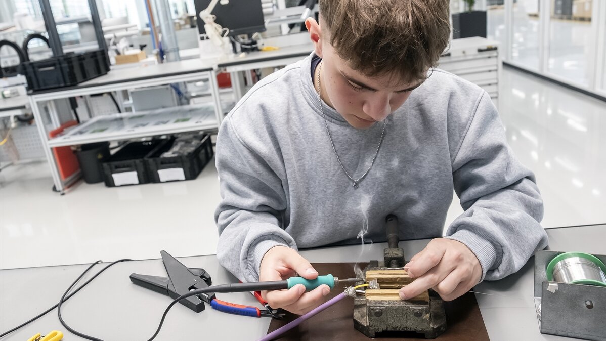 Fabian lötet das Kabel an den Stecker.