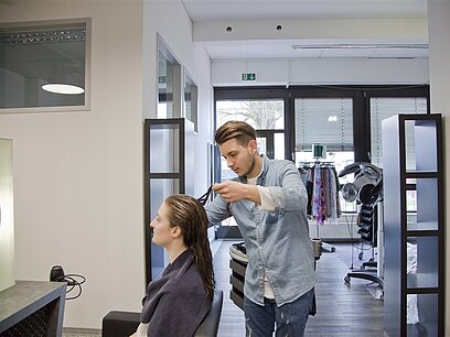 Eine Frau lässt sich von einem Friseur die Haare schneiden.
