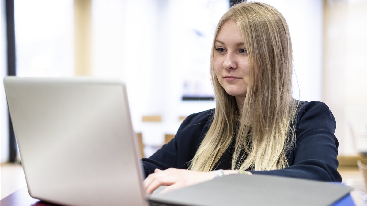 EIne Junge Frau sieht auf ihren Laptop und sucht einen Ausbildungsplatz