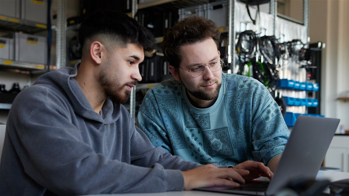 Manuel und ein Kollege aus der Regie besprechen sich vor einem Laptop.