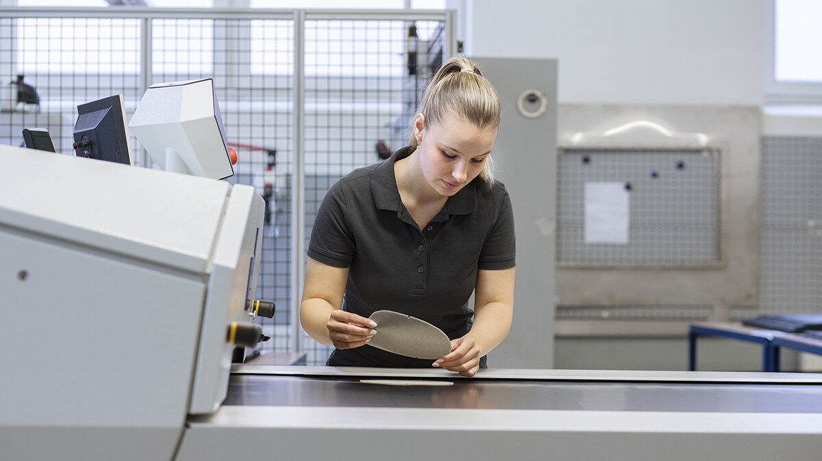 Eine junge Frau überprüft die Arbeit einer Maschine.