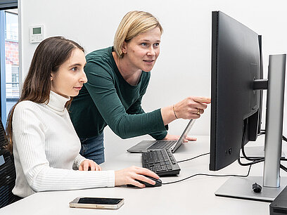 Eine Frau zeigt einer Jugendlichen etwas am Computer.