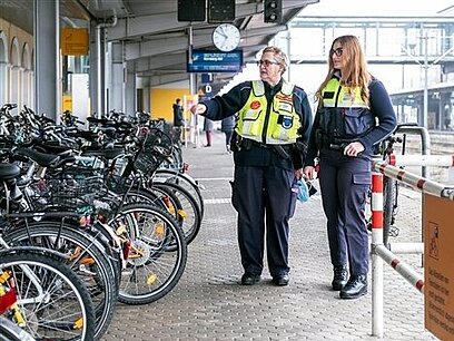 Zwei weibliche Fachkräfte für Schutz und Sicherheit kontrollieren Fahrräder am Bahnhof.