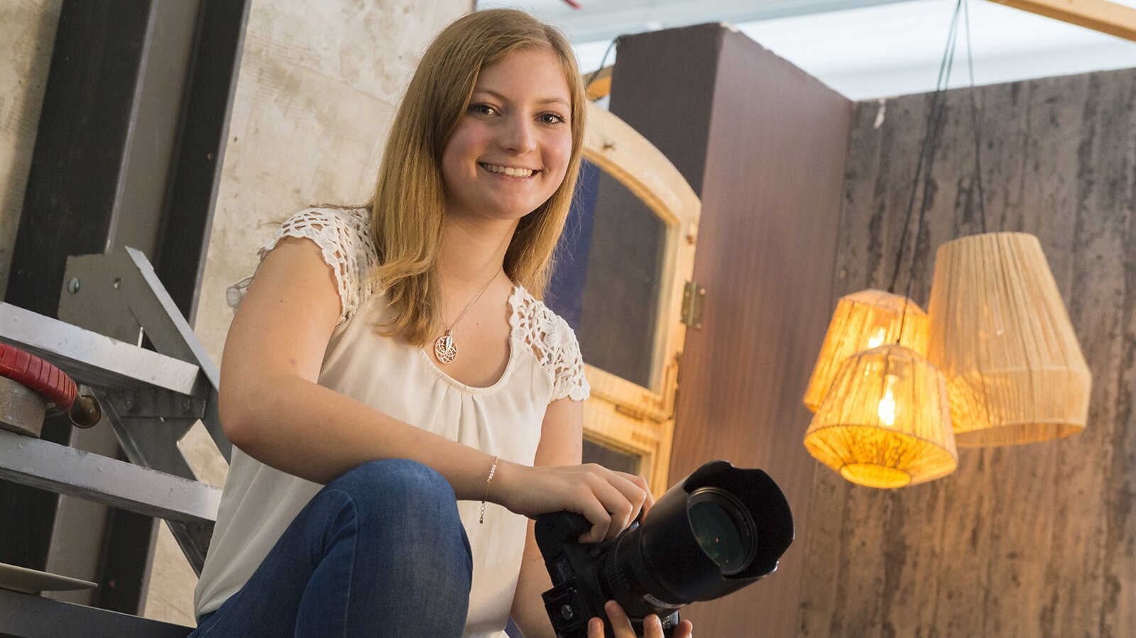Porträt von Corinna mit Spiegelreflexkamera in der Hand.