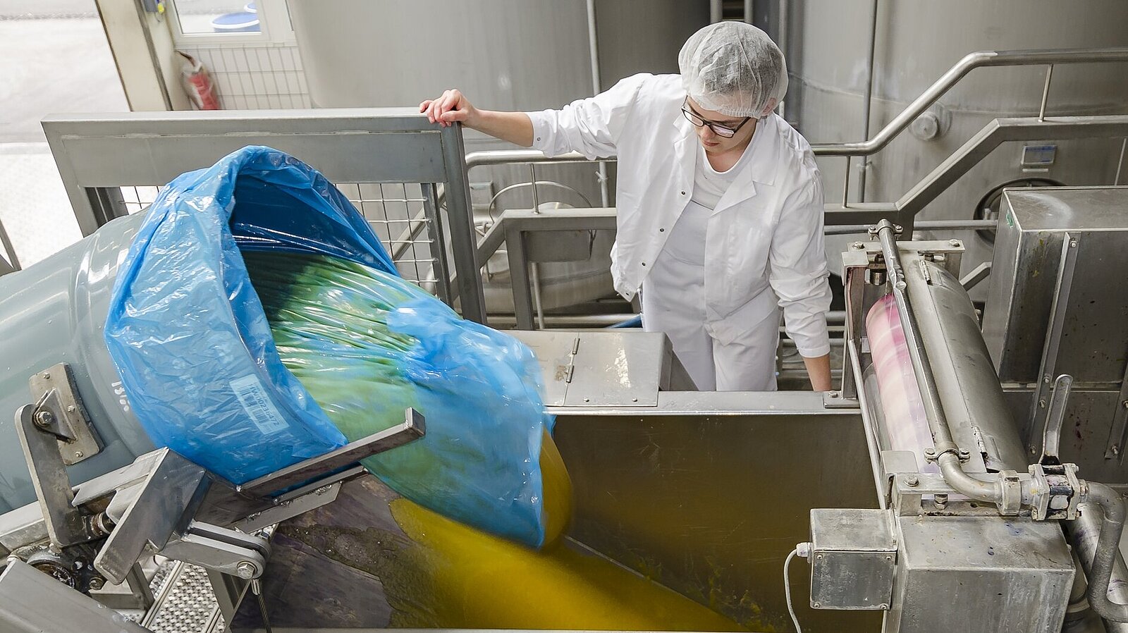 Eine Frau leitet ein angeliefertes Saftkonzentrat in die Produktionsanlage ein.