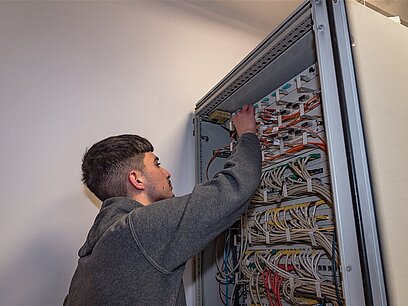 Ein junger Mann arbeitet an einem Stromkasten.