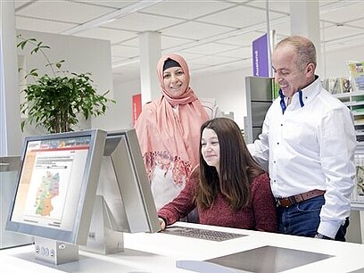Eine junge Frau arbeitet mit ihren Eltern am Computer im Berufsinformationszentrum.
