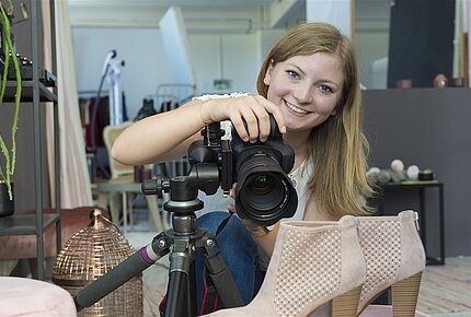 Eine junge Frau hält eine Kamera in den Händen.