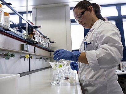 Eine junge Frau arbeitet mit Schutzkleidung in einem Labor.
